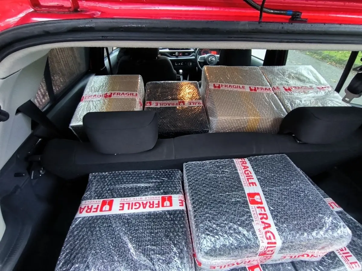 Bungkusan berpelekat Fragile memenuhi tempat duduk belakang kereta